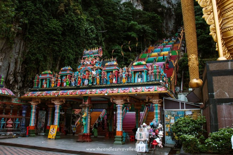 Closer view of the temple entrance at Batu Caves, showcasing the vivid carvings of Hindu gods and goddesses and the steep, colorful staircase that climbs into the forested cave above.